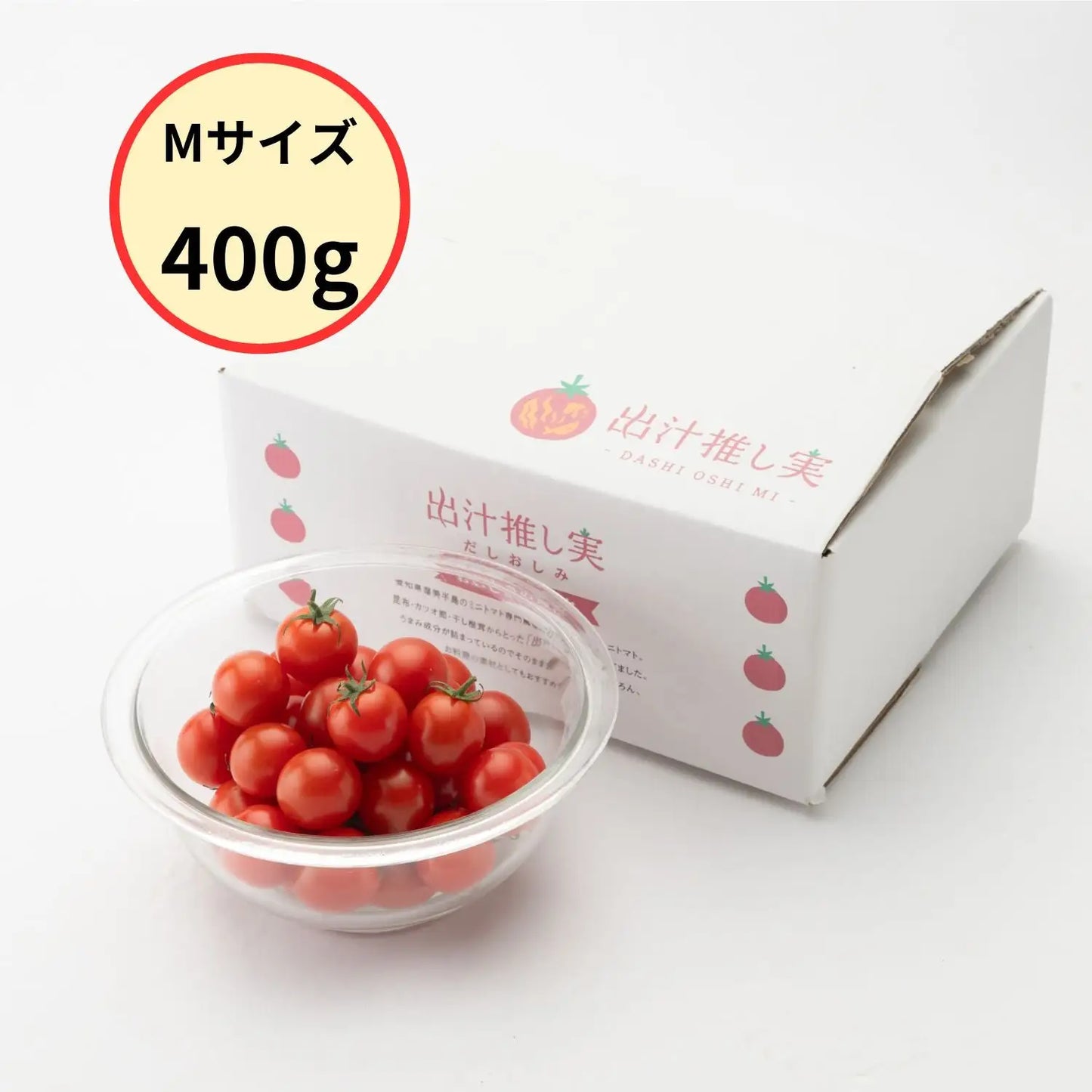 白い化粧箱「出汁推し実」とガラス容器に山盛りの完熟ミニトマト、「Mサイズ400g」の丸いバッジ入り商品写真